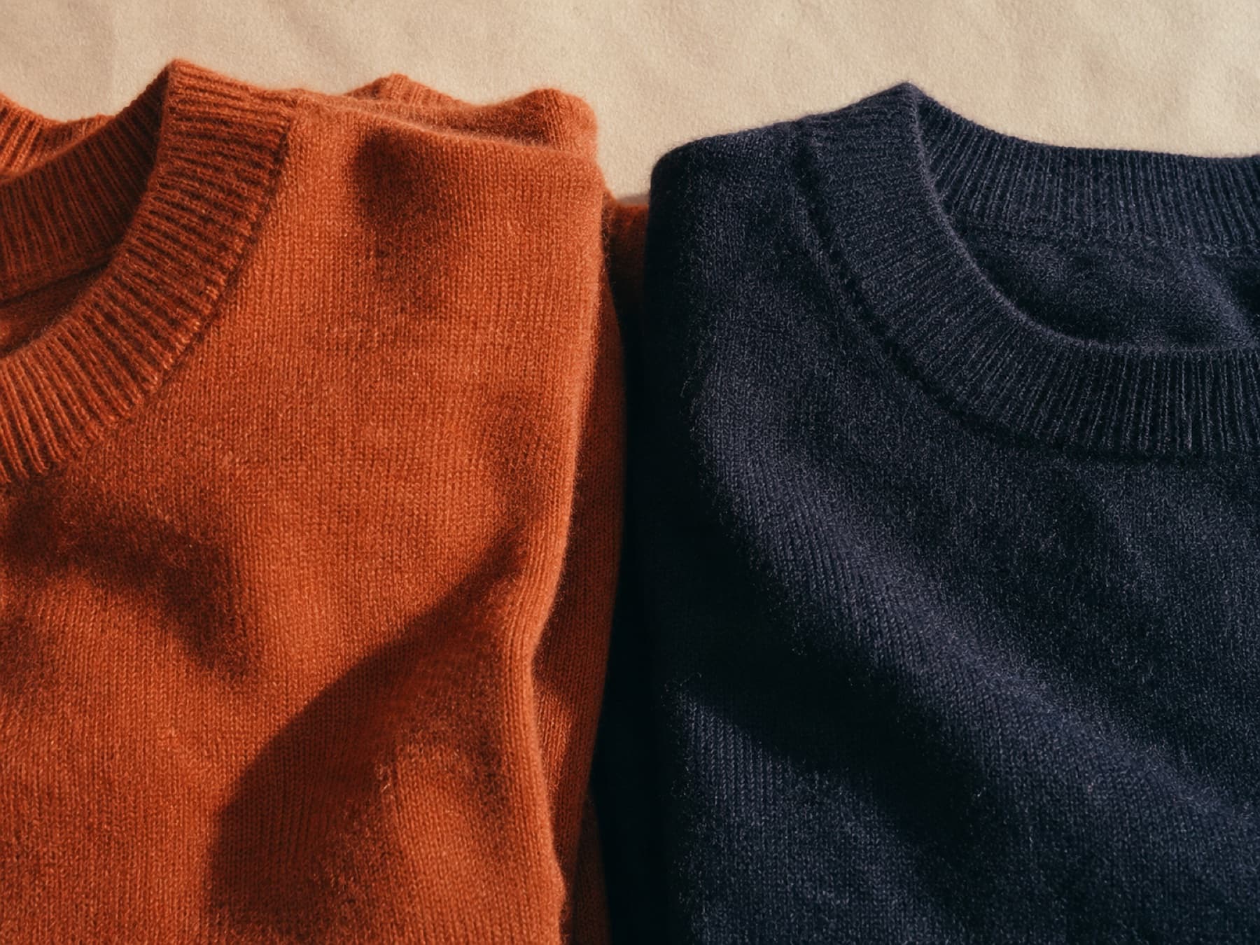 Two folded garments placed side by side on paper, one rust and one navy, compared against each other